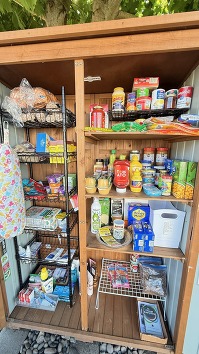 Food pantry filled with canned goods rice beans tortillas hygiene products sunscreen pet supplies a little notebook to write thanks in or requests