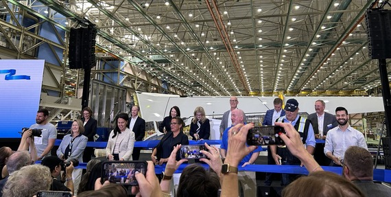 Elected officials smile while preparing to cut a blue ribbon 
