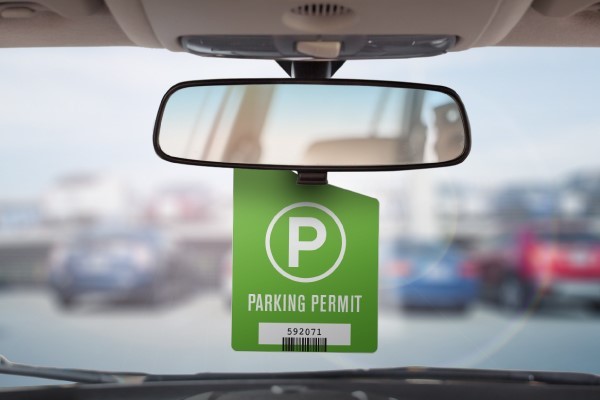 A parking permit hangtag hangs from a vehicle's rearview mirror.