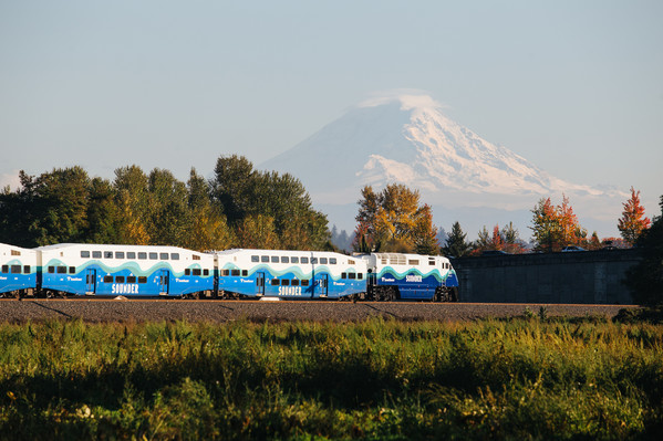 Sounder train going through, with mountain in the back. 