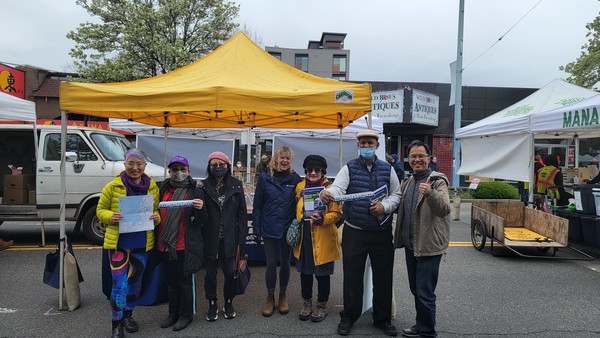 A group gathered in front of a tent with Sound Transit maps and fact sheets.