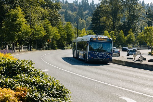 Image of a Sound Transit Route 522 bus traveling on a tree-lined road, Stride S3 Line