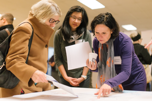 Photo of people around a table viewing information