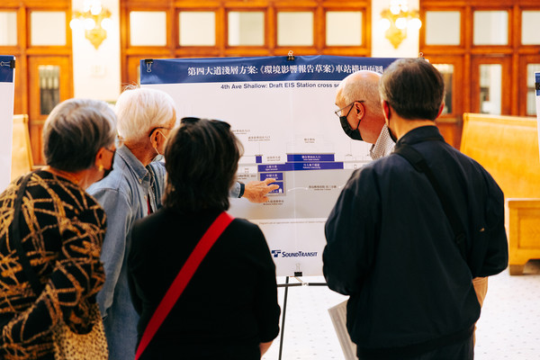 Photo of people standing in front of an information board, West Seattle and Ballard Link Extensions Project update header image