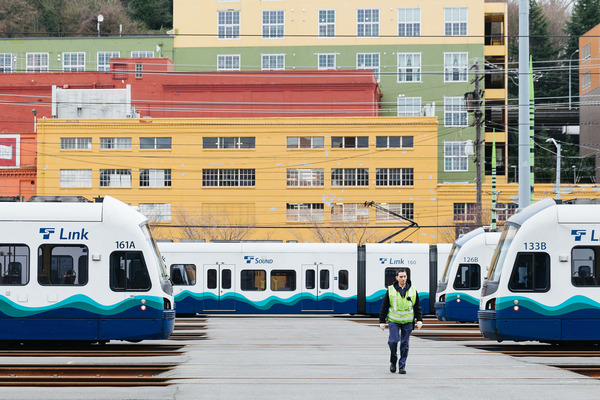 photo of a person walking between several link light rail vehicles at the Operations and Maintenance Facility