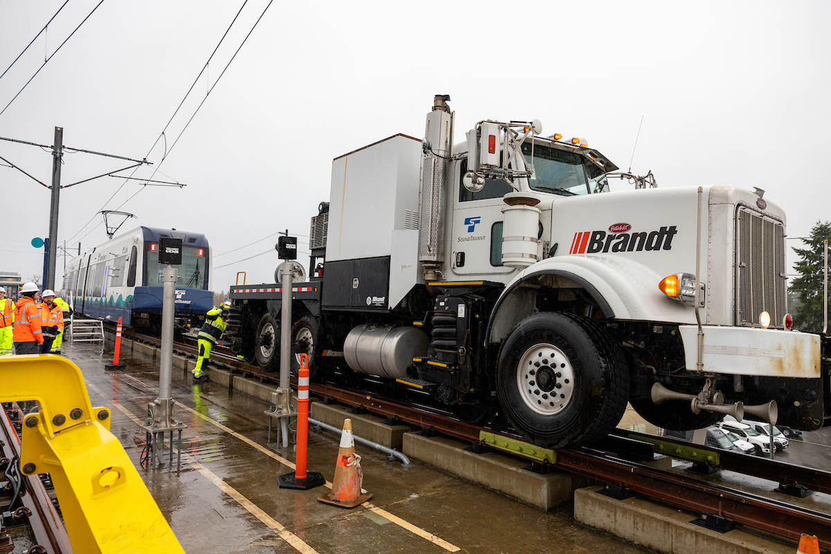 Photo showing a light rail vehicle being connected to a truck to perform a “dead car tow".