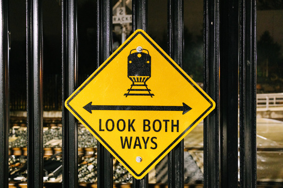 A sign saying “Look both ways” encourages riders to look out for trains before crossing the tracks.
