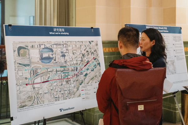 Photo of people viewing an information poster board at Ballard Link Extension Open House