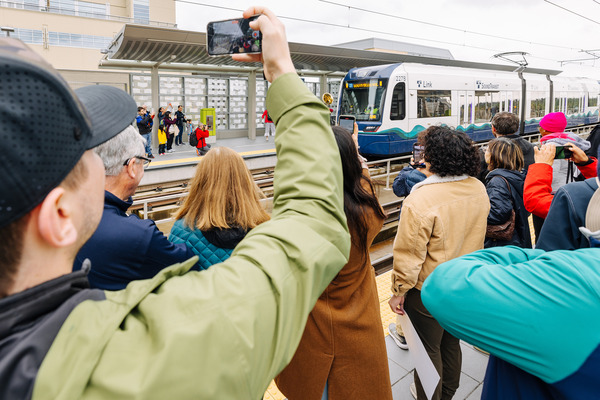 Photo of people taking photos of link train arriving at a station during the 2 Line opening day
