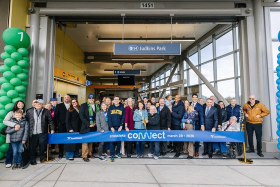 Photo of the ribbon cutting at Judkins Park Station with a large group of people standing and smiling in front of the ribbon.