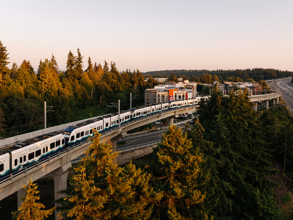 Photo of a train traveling along tracks at dusk on a clear day. 