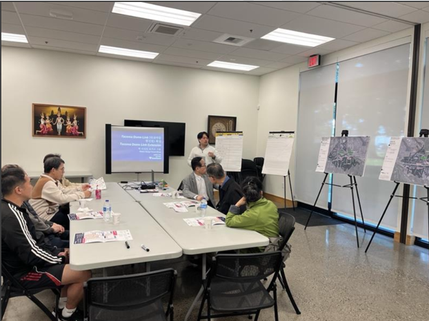A person is presenting in a meeting room as several people look on.