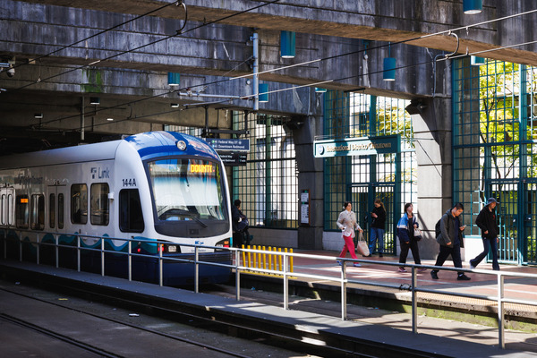 Sound Transit Link light rail train arrives at the International District/Chinatown station, as passengers walk along station platform.