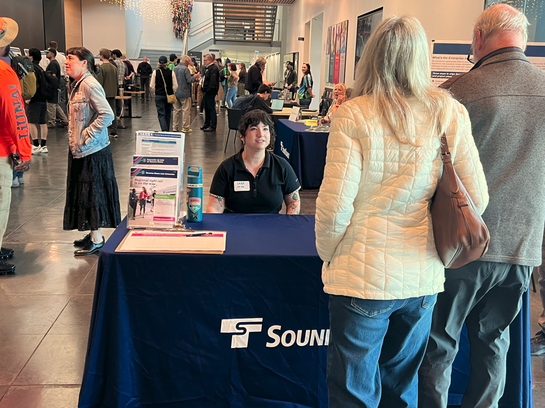 A photo of people interacting at an information table during a Sound Transit event.