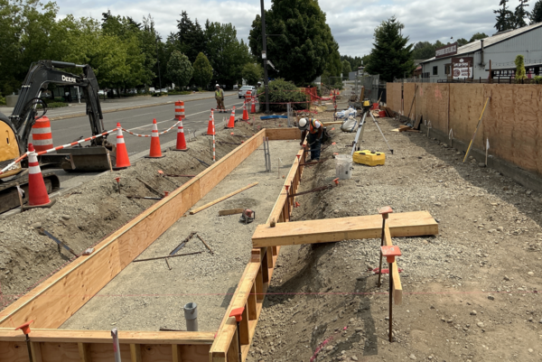 Construction crews work on the first shelter footing foundation with formwork.