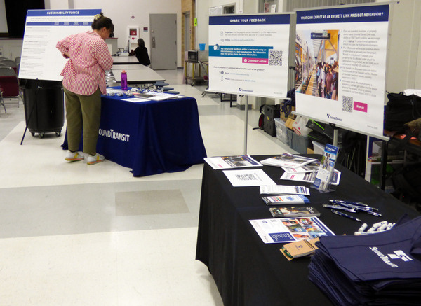 A person reads materials at a table of information at a Sound Transit event. 