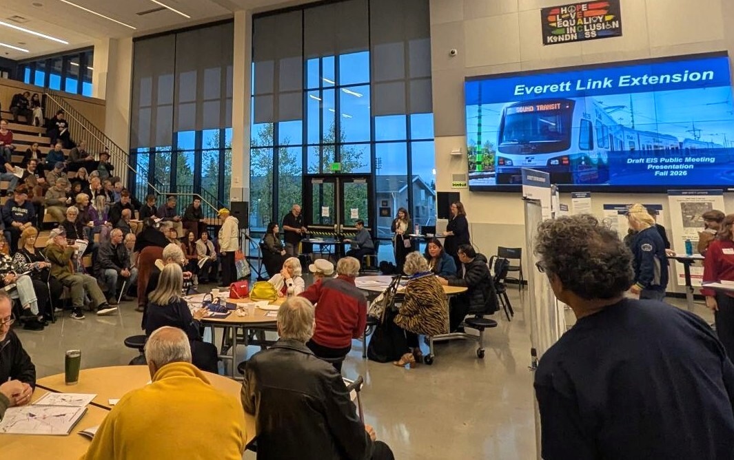 Photo of community members attending a Sound Transit event in a large hall with stadium seating.