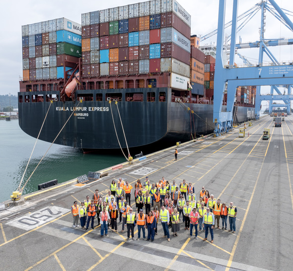 CM Bushnell in a crowd of folks in front of a large ship at the completion of shore power at Husky Terminal event