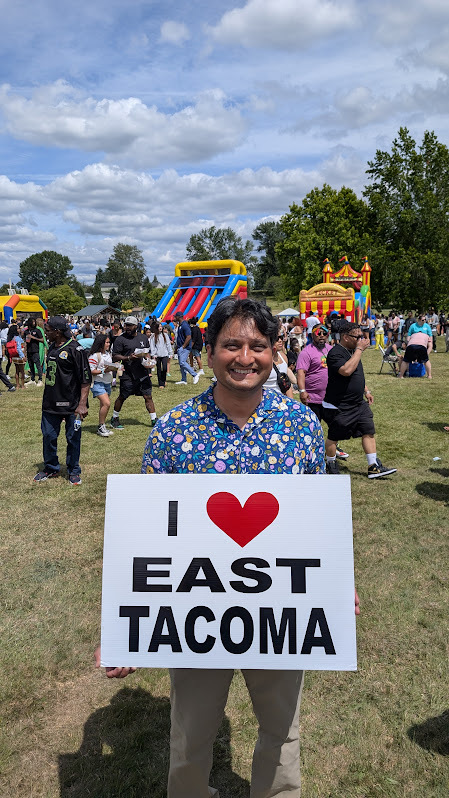 CM Sadalge at Juneteenth celebration holding an "I heart East Tacoma" sign