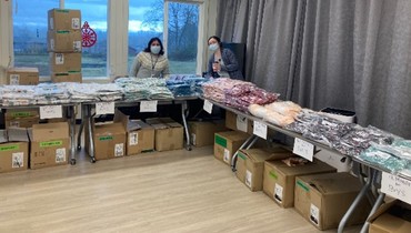 Elodia Andres Cornelio and Rachel Hauser posing behind tables topped with clothing.