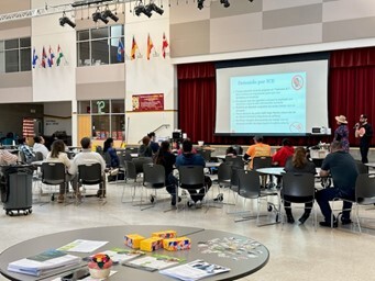 Groups sitting around tables in a gym.