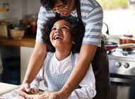 Smiling adult and child baking together.
