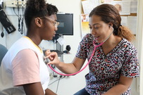 Woman using stethoscope to listen to young woman's heart.