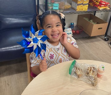 Little girl smiling and holding a pinwheel.