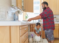 Man and girl loading dishwasher.