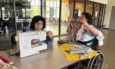 Two people sewing at a table.