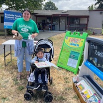 Woman standing next to baby in stroller at a free lunch event in Tacoma.