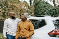 Smiling man with his arm around the shoulders of a smiling teen boy.