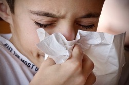 Child holding tissue over nose.