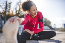Athletic woman sitting on the ground stretching her legs.