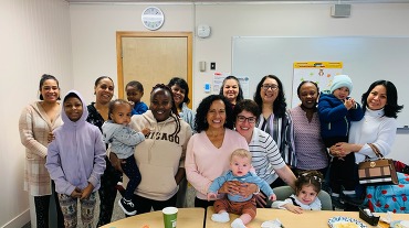 Group of women and babies in a classroom setting.