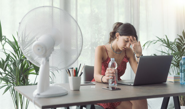Woman cooling herself with an electric fan.