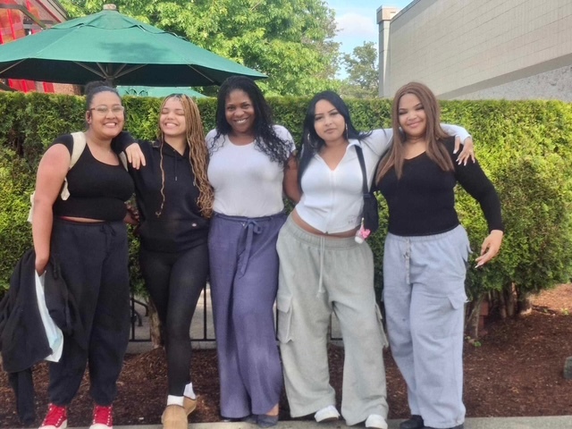 Five teenage girls arm-in-arm posing for the picture.