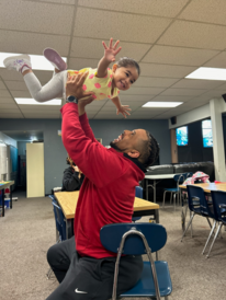 Smiling dad holding his happy daughter above his head in a flying position.