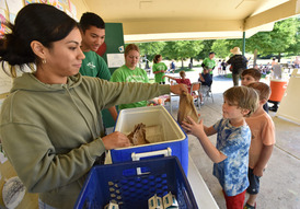 Woman handing a lunch bag to a child.