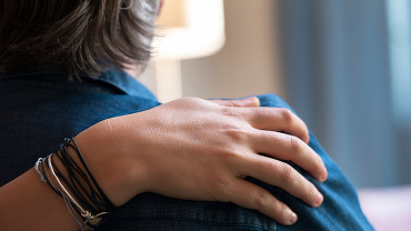 Comforting hand on shoulder of a man.