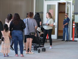 People in a line waiting to enter a building.