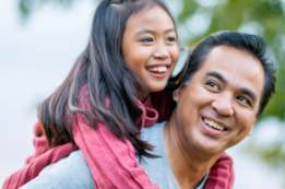 Smiling girl riding picky back on her smiling Dad's back.