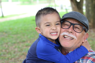 Smiling boy hugging his grandfather.