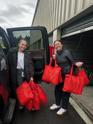 Two women unloading care bags from a minivan.