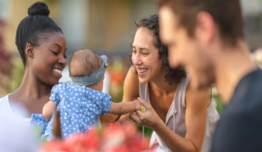 Smiling people with one woman holding a baby.