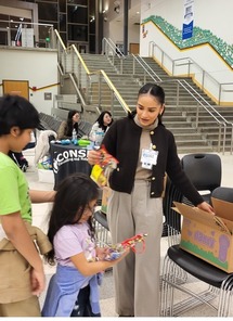 Woman giving a child a resource pack at a school.