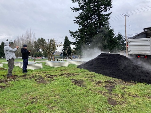 Two men watching a dump truck delivering soil.