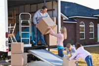 Family loading moving boxes into moving truck