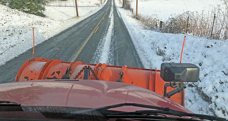 Snow plow pushes snow on local roadway