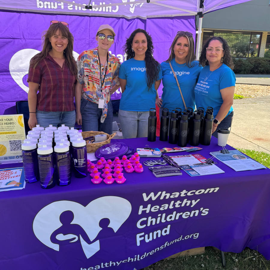 Five people standing behind a Healthy Children's Fund table with handouts and freebies.
